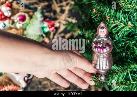 Hand hanging up his on the Christmas tree Christmas-tree decorations toy in the form of Snow Maiden. Stock Photo