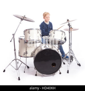 young blond boy drums behind drum kit against white background in studio Stock Photo