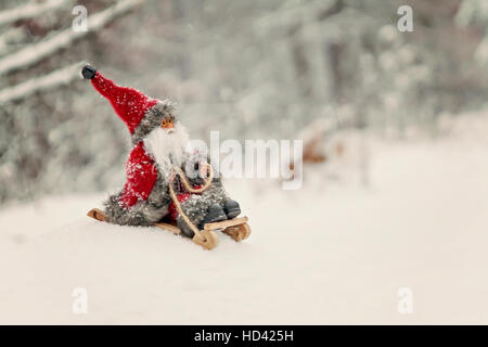 Toy Santa Claus on a sledge in a snowy forest. Stock Photo