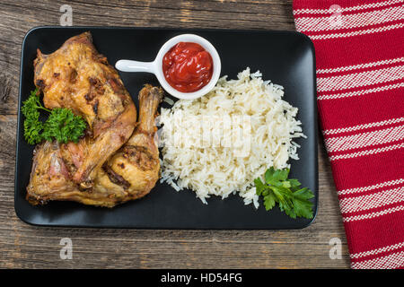 Grilled chicken thighs with rice on the table with cutlery Stock Photo