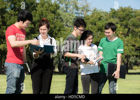 Group of Asian young attractive smiling students dressed casual standing on park outdoors in campus at the university. University student. Stock Photo