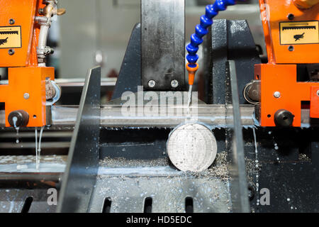 Band saw machine cutting tool steel bar by automatic feed working in factory. Closeup at machine. Stock Photo