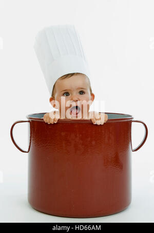 Infant wearing a chef's cap in a pot Stock Photo