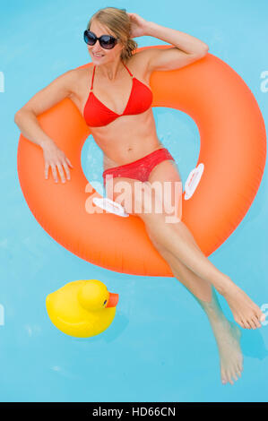 Young woman relaxing in a floating tire in a pool Stock Photo
