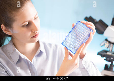 MODEL RELEASED. Woman holding micro plate in laboratory. Stock Photo