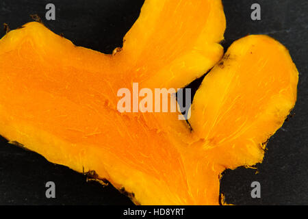 Piece of turmeric or Curcuma longa root on slate background, macro. Stock Photo