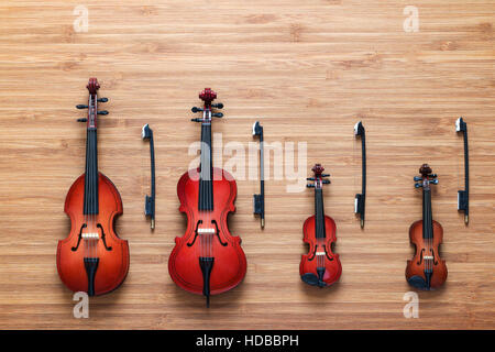 Set of four toy string musical orchestra instruments: violin, cello, contrabass, viola on a wooden background. Quartet. Music concept. Stock Photo