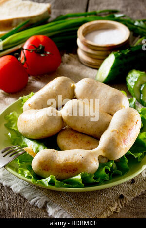 Homemade chicken sausage meat and various vegetables, herbs on rustic background. Stock Photo