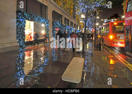 Rainy day in London UK Oxford street with Xmas shoppers and Christmas decorations outside Selfridges West End department store  just stopped raining Stock Photo