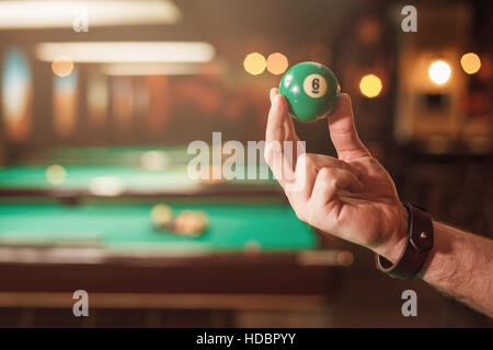 Male hand shows a billiard sphere number eight. Stock Photo