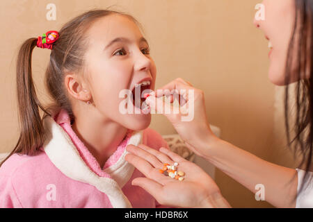Hand puting tablet in a mouth to the little girl Stock Photo