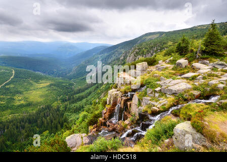 Beautiful waterfall above a deep green valley in summer mountains Stock Photo