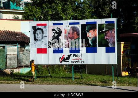 Woman walking past billboard with images of iconic Cuban president Fidel Castro in Havana, Cuba Stock Photo