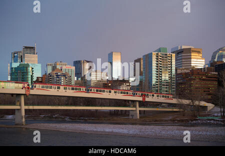 Light rail electric train powered by wind energy crossing Bow River to downtown Calgary, pedestrian bridge underneath Stock Photo