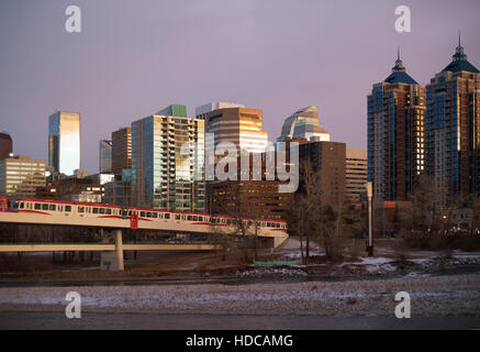 Light rail electric train powered by wind energy crossing Bow River into downtown Calgary, pedestrian bridge underneath Stock Photo