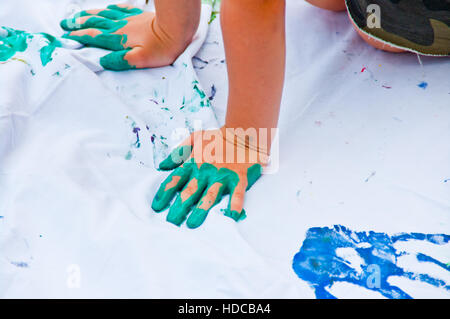 children playing making colorful designs with hands dipped in colored dye Stock Photo