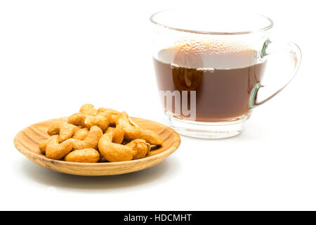 Salty cashew nuts in wooden plate and a cup of coffee on white background Stock Photo