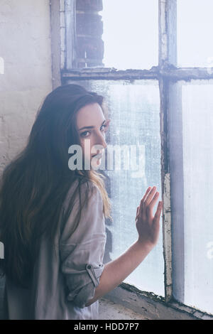 Sad woman leaning on the window Stock Photo