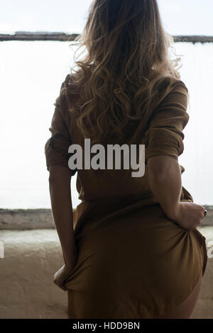 Rear view of a woman standing by the window Stock Photo