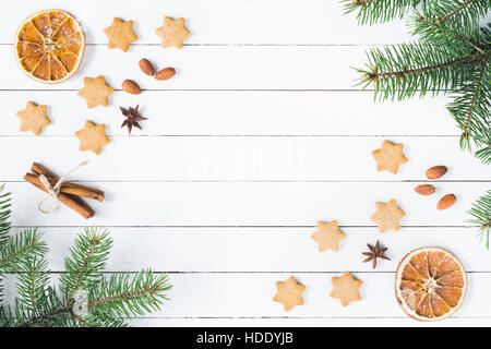 Christmas frame with gingerbread stars cookies, spices and fir tree branches on white background Stock Photo