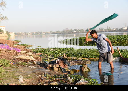 An Indian washerman of a local laundry washing clothes on the bank of a lake in Muzaffarpur, India. Stock Photo