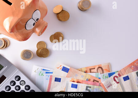 Concept savings and accounting with piggy bank and stacked coins and bills, and calculator on table and white background. Horizontal composition. Top Stock Photo