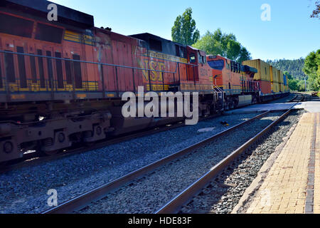 Multiple BNSF diesel locomotives in the middle of long train of shipping containers at Flagstaff, Arizona Stock Photo