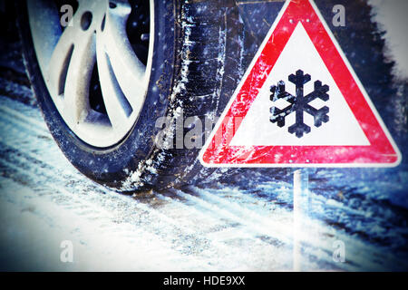 Car tires on winter road with traffic sign Stock Photo