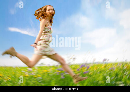 Happy girl jumping high on a flower field Stock Photo