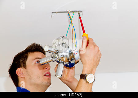 Portrait of electrician installation a new lamp in house Stock Photo