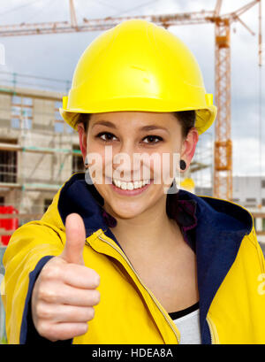 Young woman in work wear with thumb up Stock Photo