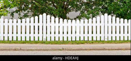 White, wooden fence in front of a garden Stock Photo