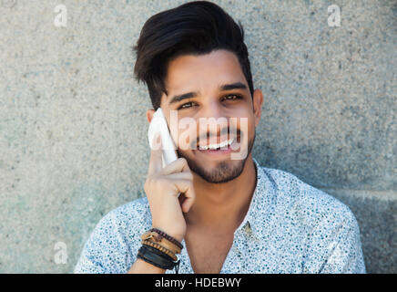 Handsome hipster with beard laughing at phone outdoor in the summer Stock Photo