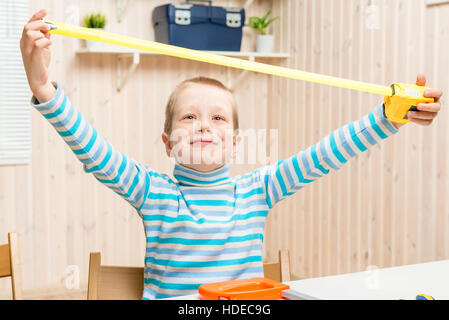 6 years old boy in the garage with a measuring tape Stock Photo