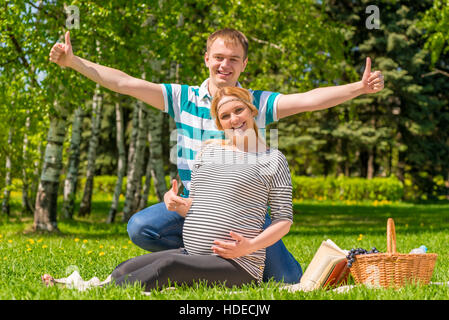 Happy pregnant couple showing thumbs up gesture with hands Stock Photo