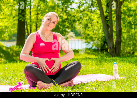 beautiful pregnant woman showing heart symbol hands near the abdomen Stock Photo