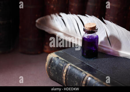 Vintage still life with inkwell near quill on old book Stock Photo