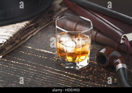 Whiskey with pipe , hat and newspaper on the wooden table Stock Photo