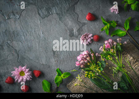 Flowers  , raspberries and mint on the dark stone background Stock Photo