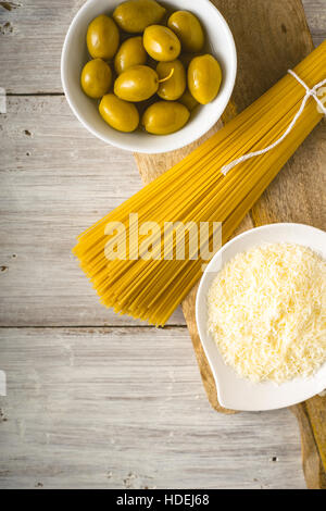 Raw spaghetti with olives and cheese on the white wooden table vertical Stock Photo