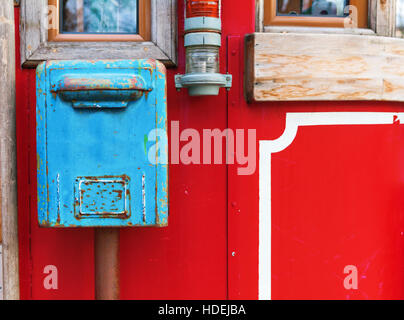 old blue mailbox hanging on red wall. Stock Photo