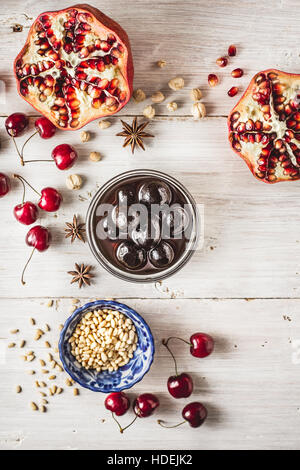 Still life with pomegranate , cherry and spices on the white wooden table. Concept of oriental fruits Stock Photo