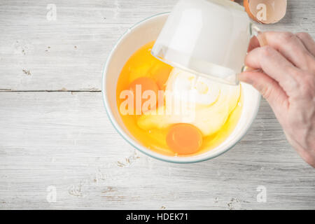 Mixing eggs and yogurt in the ceramic bowl top view Stock Photo