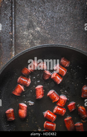 Fried smoked  sausages in the pan on the metal background vertical Stock Photo