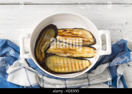 Grilled eggplants in the ceramic pan  on the white wooden table top view Stock Photo