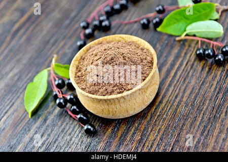 Flour of bird-cherry in a bowl with black berries on a background of wooden boards Stock Photo