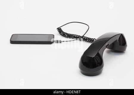 Old phone reciever and cord connection with new phone. Funny hotline concept. Stock Photo