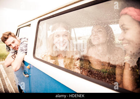 Friends in a 70's styled minivan repairing from summer rain, girls are talking and having fun Stock Photo