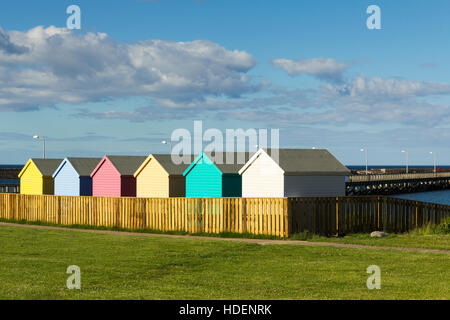 Colourful beach huts on the seafront  at Amble, Northumberland, adjacent to the harbour. Stock Photo