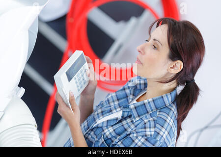 woman pressing button on security system indoors Stock Photo